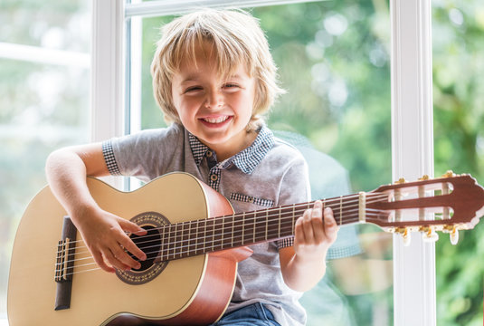 child with a smile holding a guitar